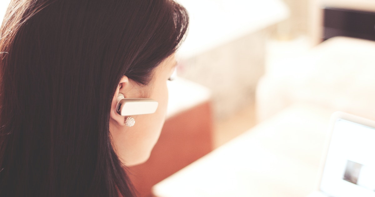 A woman listens to an earpiece